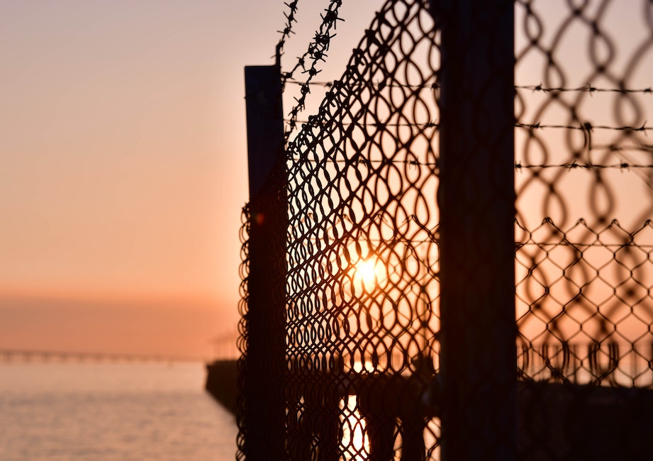 Black Metal Fence Near Sea during Sunset