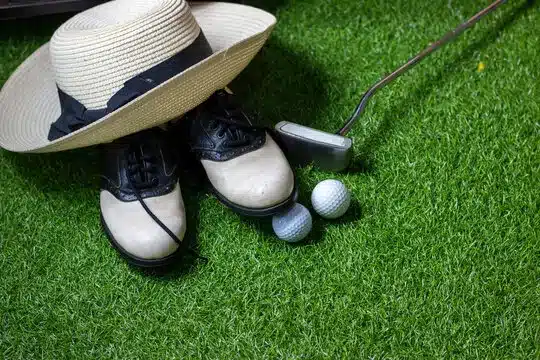 Golf ball and golf shoes are on green grass background